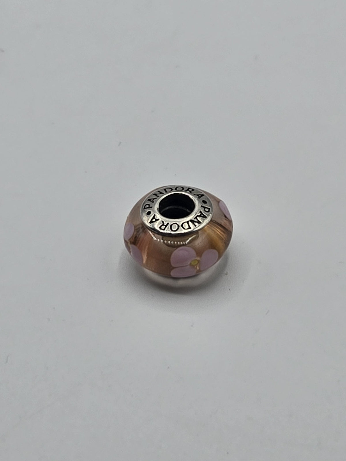 Pandora Amber and Lilac Flower Murano Glass Charm on a plain light background