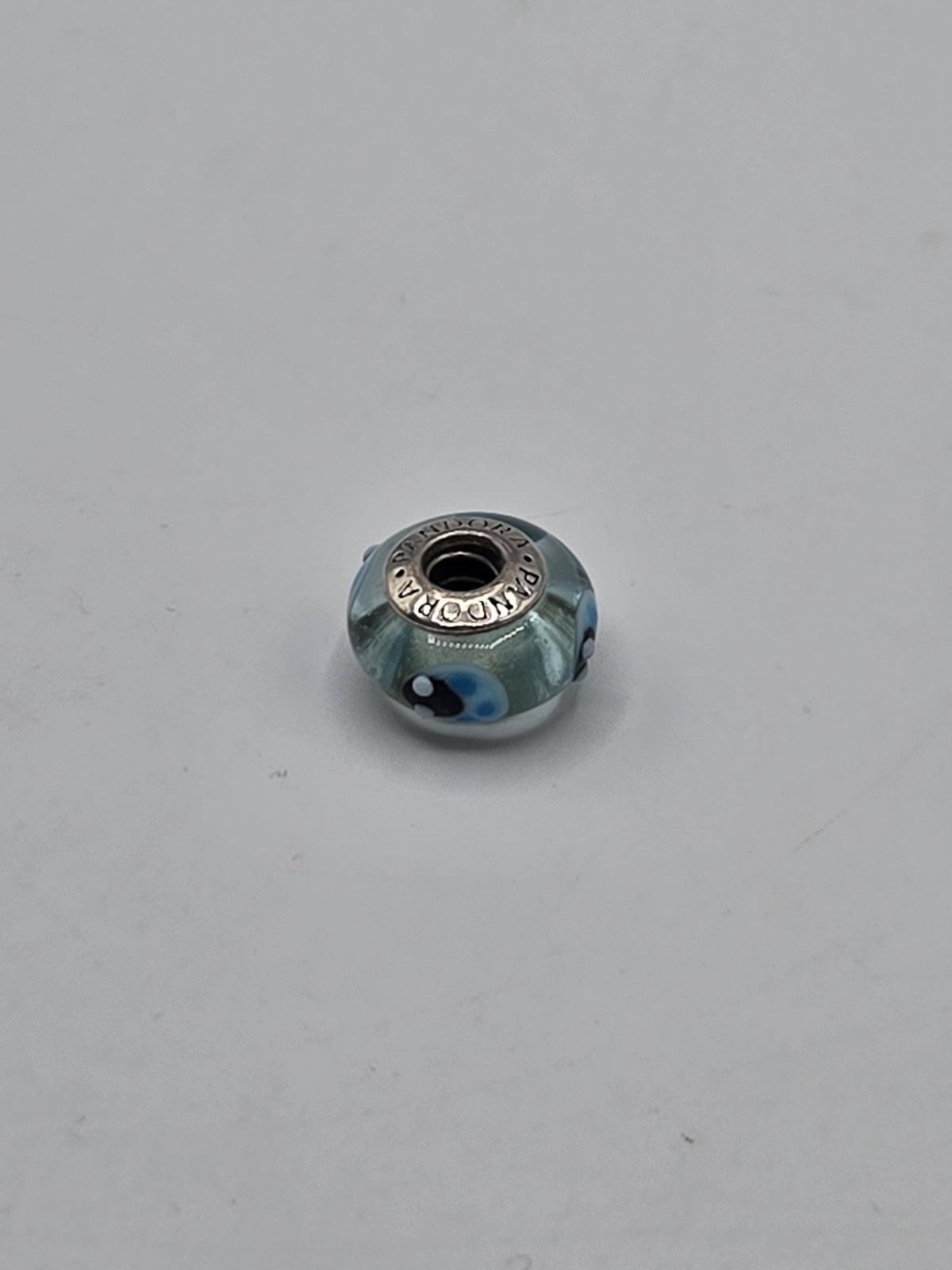 Pandora Aqua and Navy Dot Murano Glass Charm on a plain light background