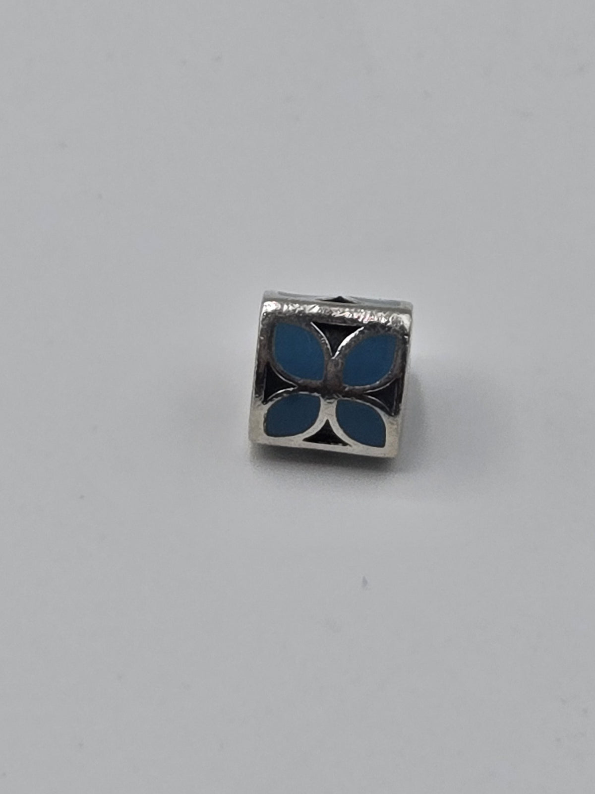 Pandora Blue Enamel Petal Triangle Charm on a plain light background