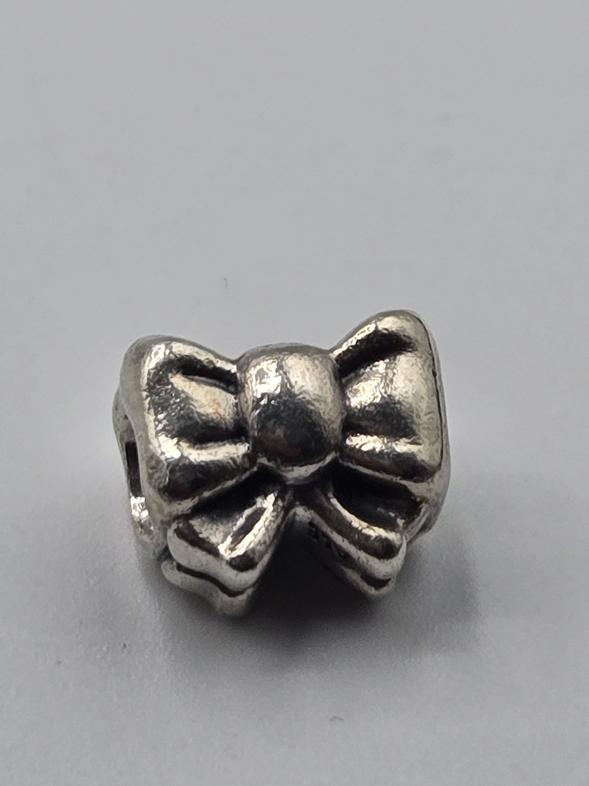 Pandora Bow Charm on a plain light background
