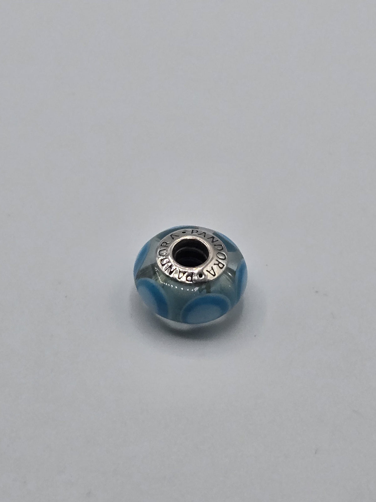 Pandora Clear and Sky Blue Circle Murano Glass Charm on a plain light background