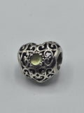 Pandora Filigree Heart Charm with Green Stone on a plain light background