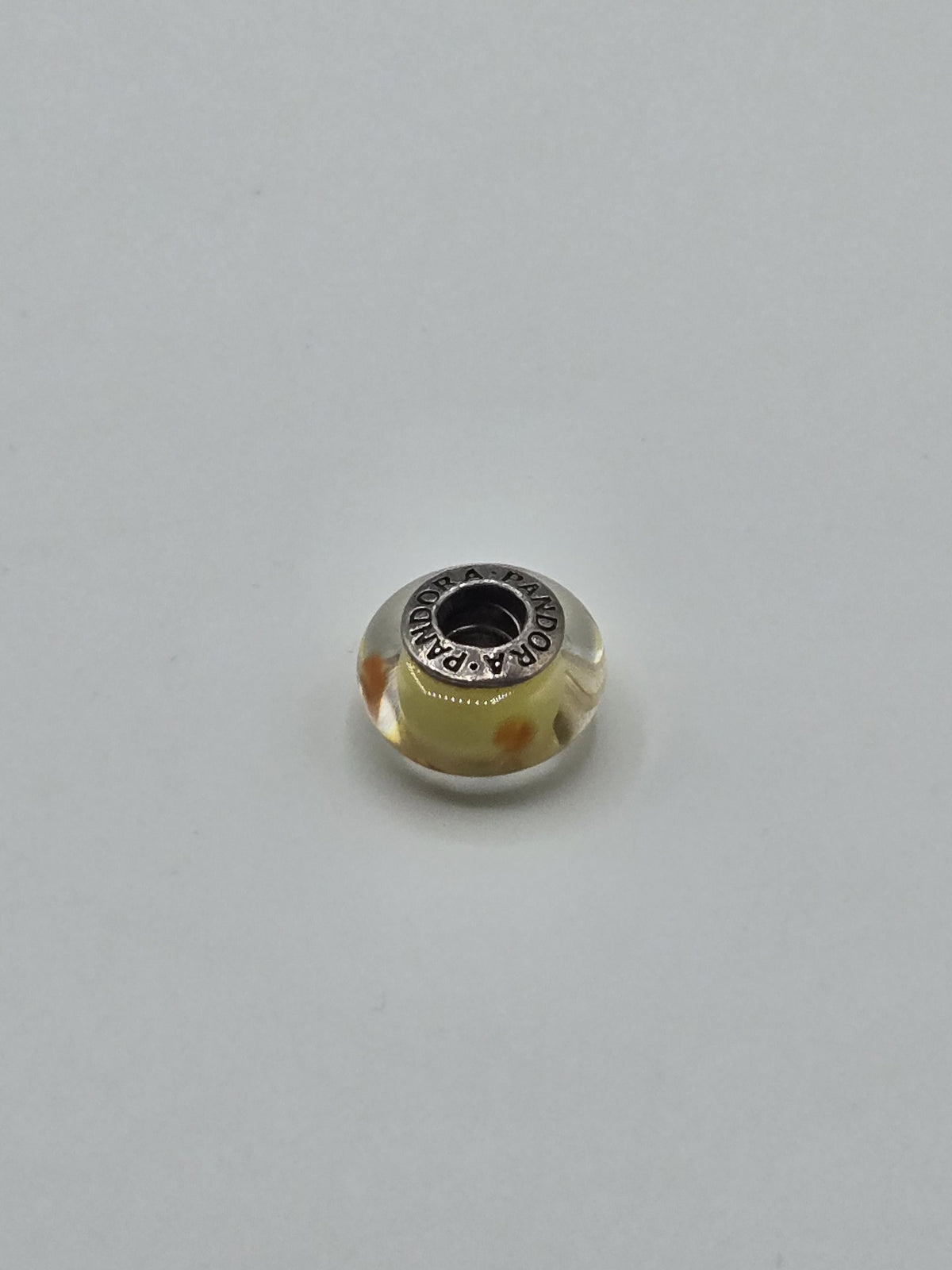 Pandora Lemon Yellow and Orange Dot Murano Glass Charm on a plain light background