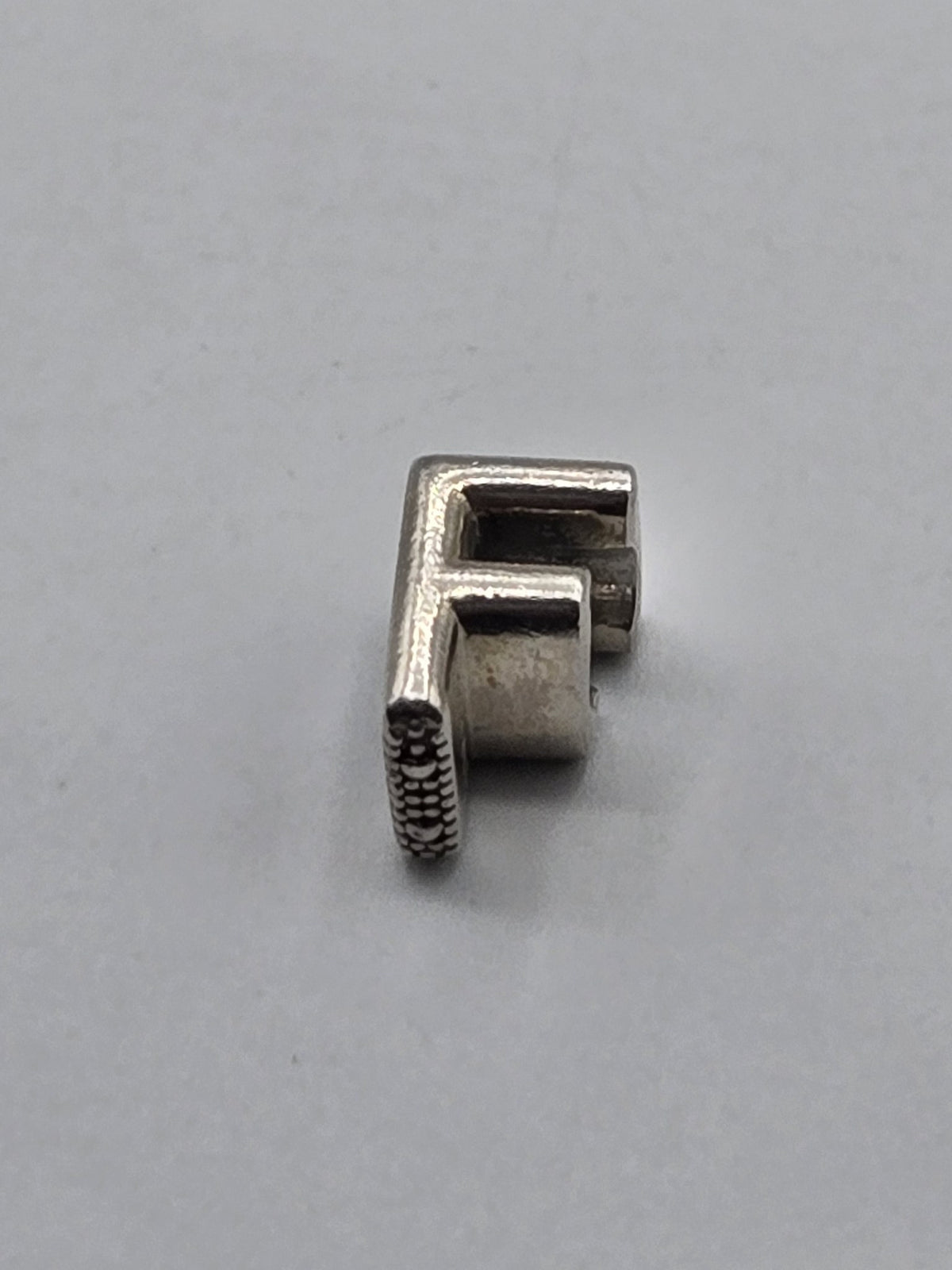 Pandora Letter F Charm on a plain light background