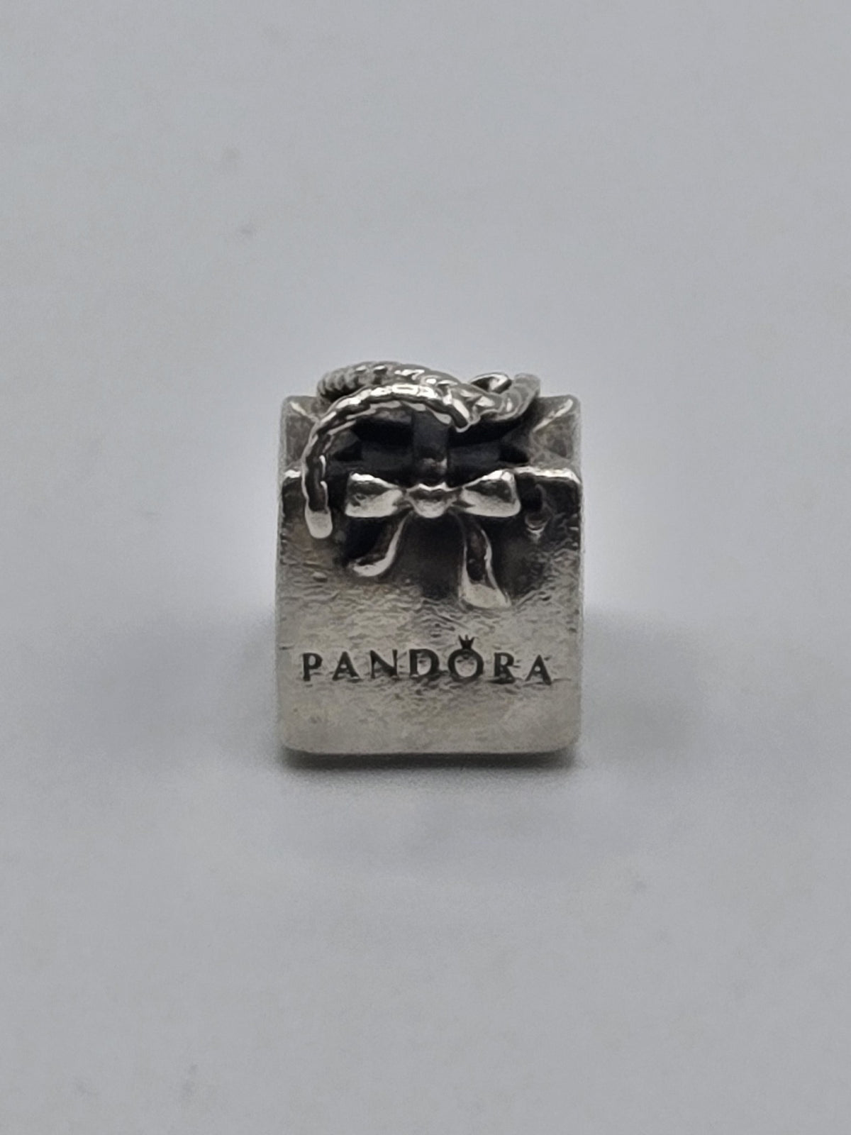Pandora Logo Gift Bag Charm on a plain light background