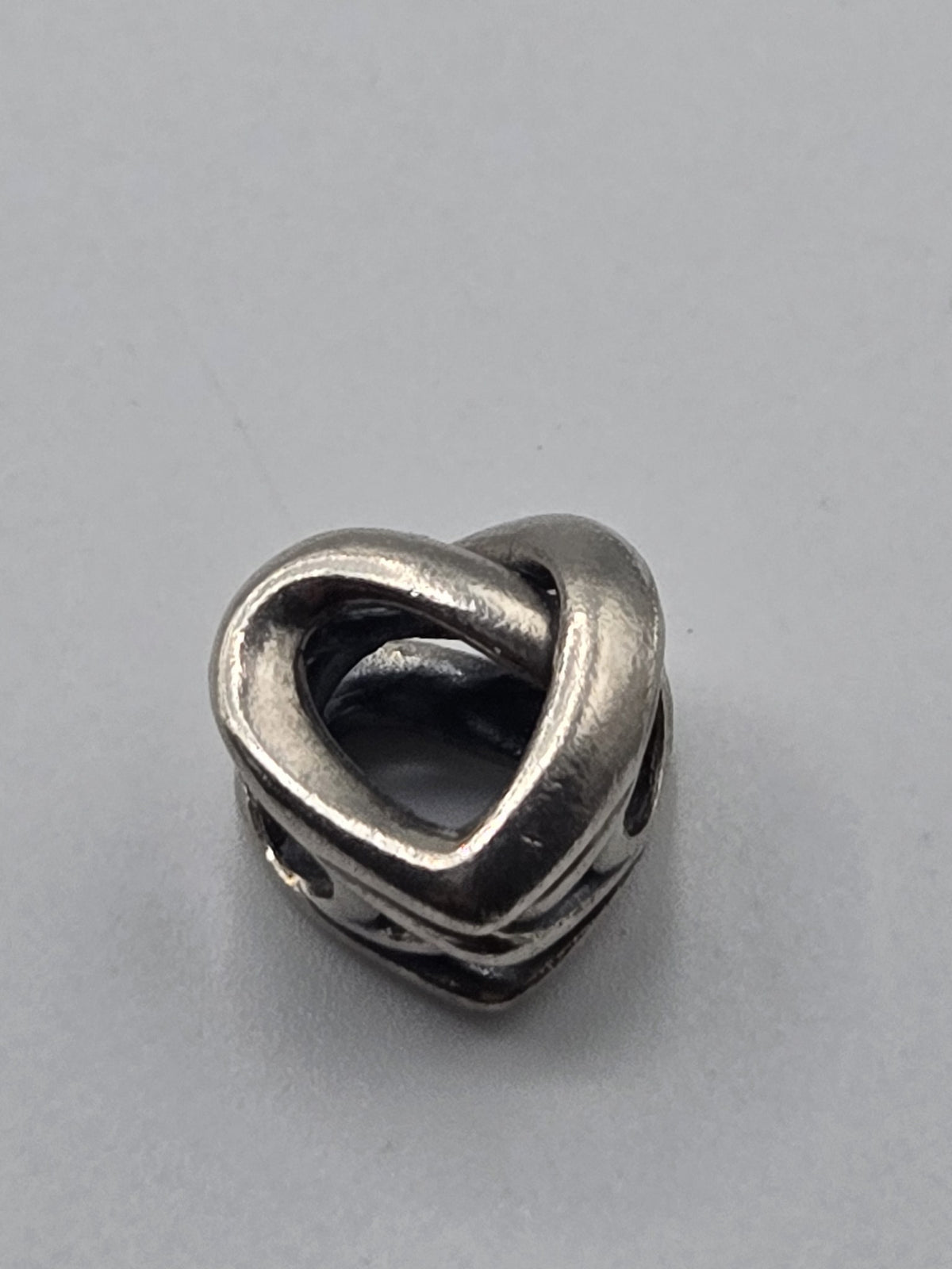 Pandora Openwork Entwined Heart Charm on a plain light background