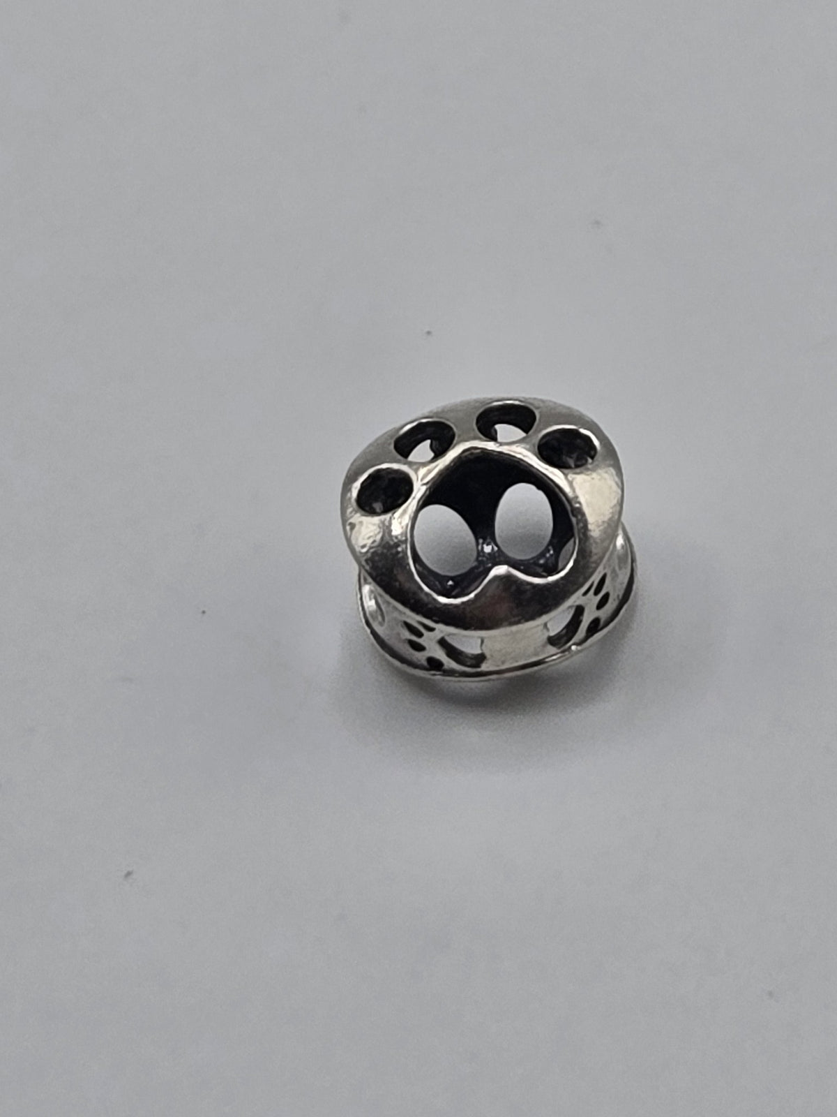 Pandora Openwork Paw Print Charm on a plain light background