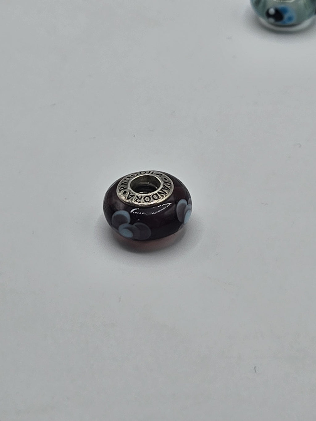 Pandora Plum and Pale Blue Flower Murano Glass Charm on a plain light background