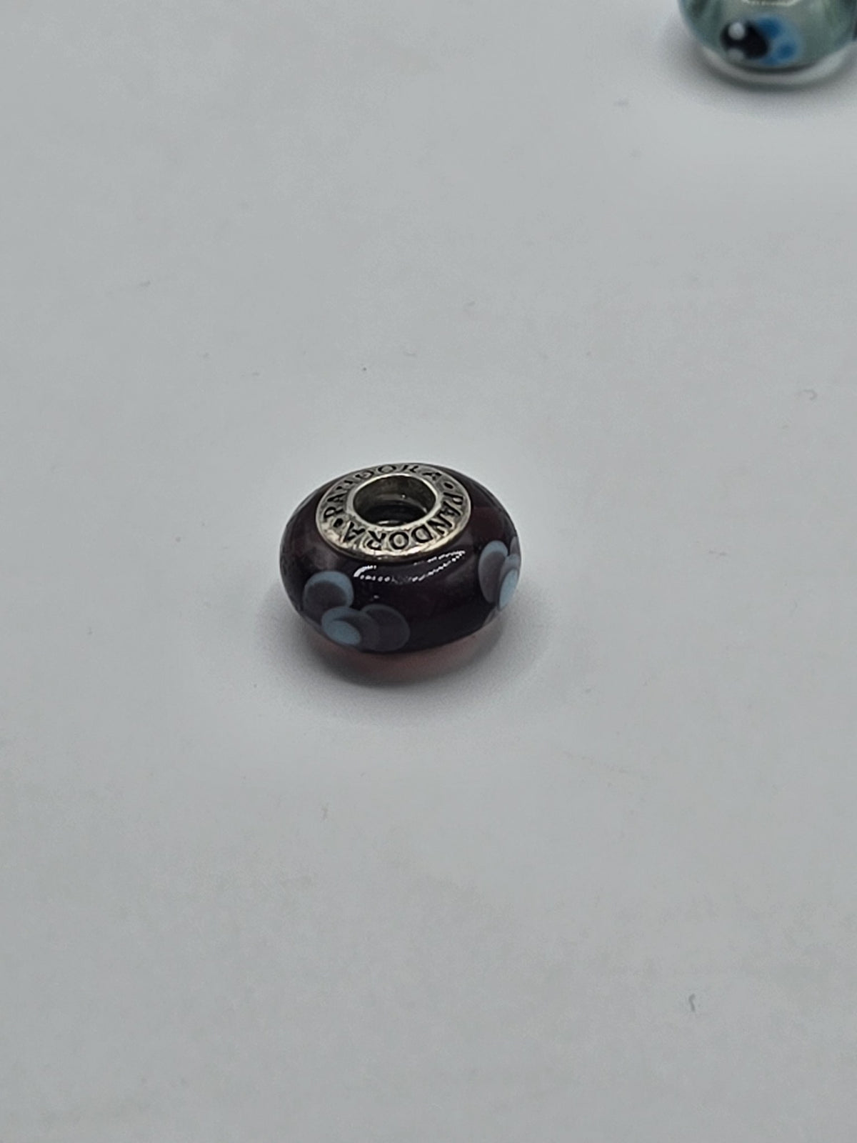 Pandora Plum and Pale Blue Flower Murano Glass Charm on a plain light background