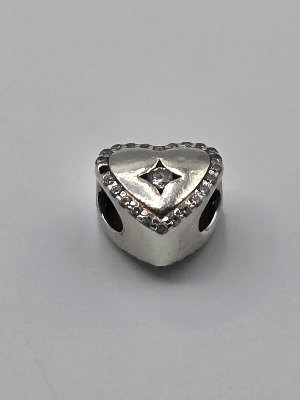 Pandora Sparkling Outline Heart Charm with Clear Stone on a plain light background