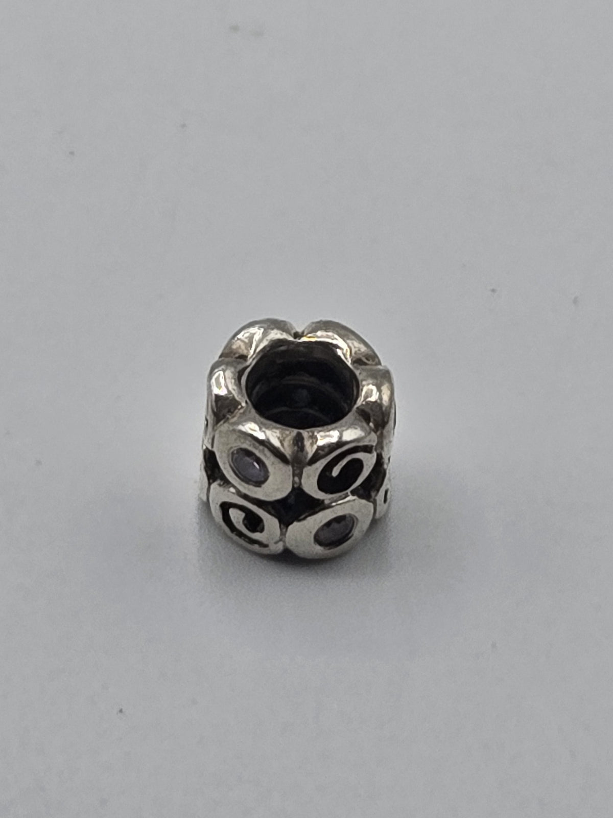 Pandora Swirl Charm with Lilac Stones on a plain light background