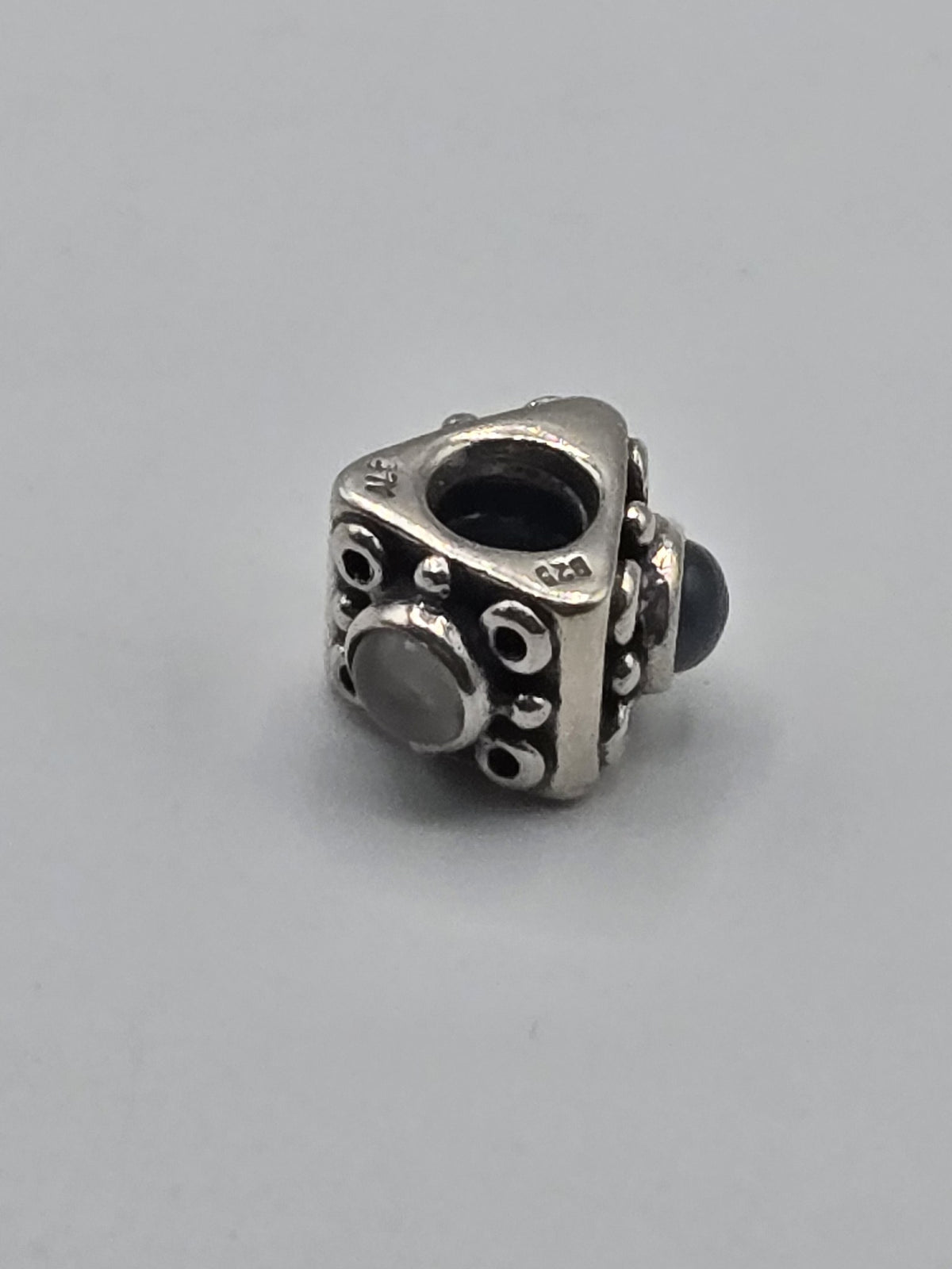 Pandora Triangle Charm with Grey Stones on a plain light background