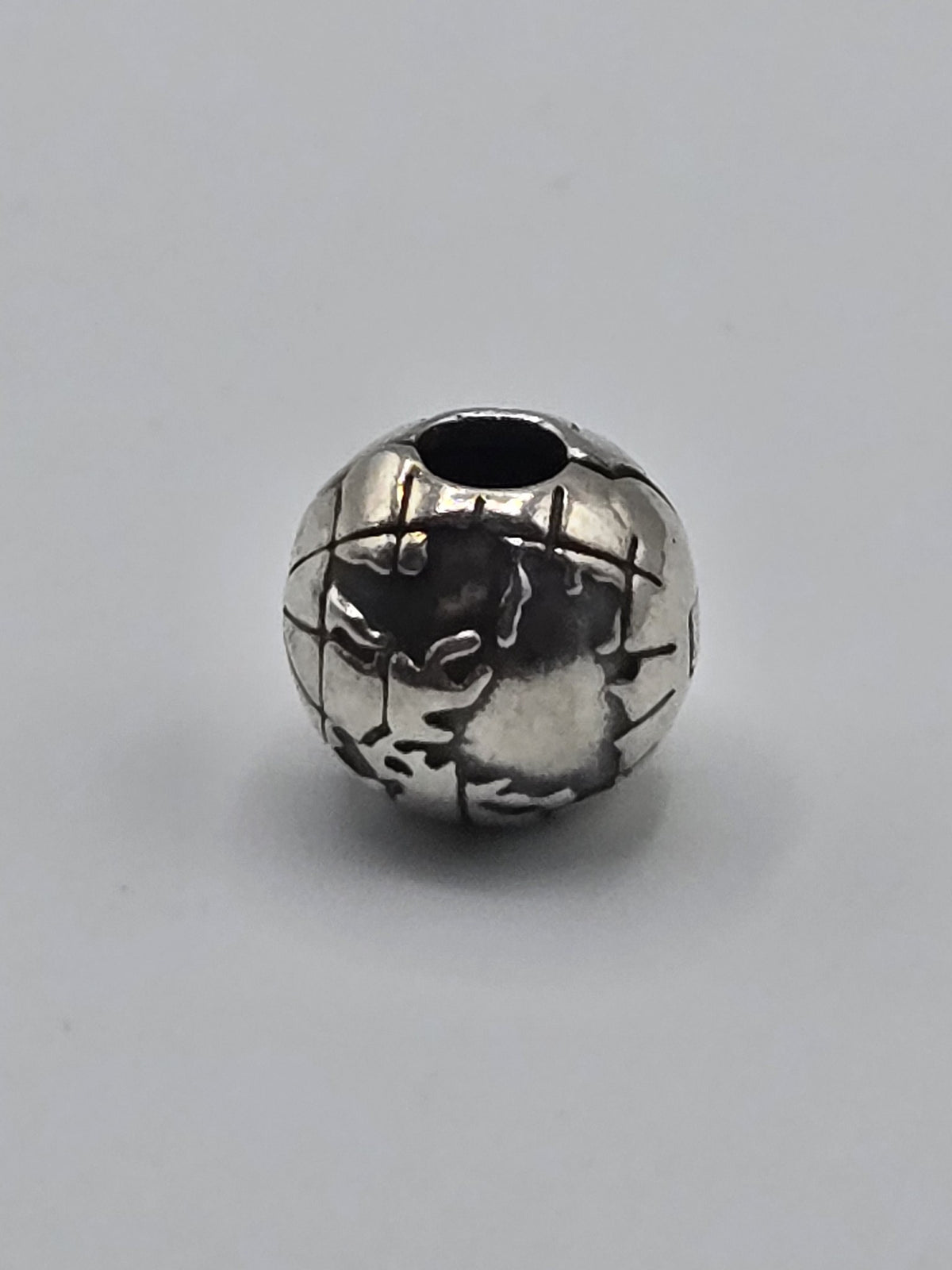Pandora World Globe Charm on a plain light background